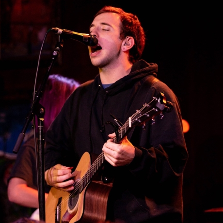 A picture of singer and songwriter Mat Kerekes holding a guitar on stage